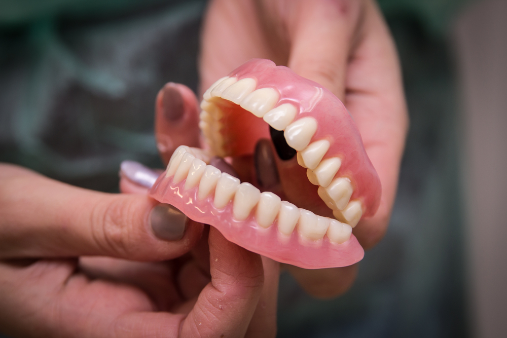 Female hands holding a denture