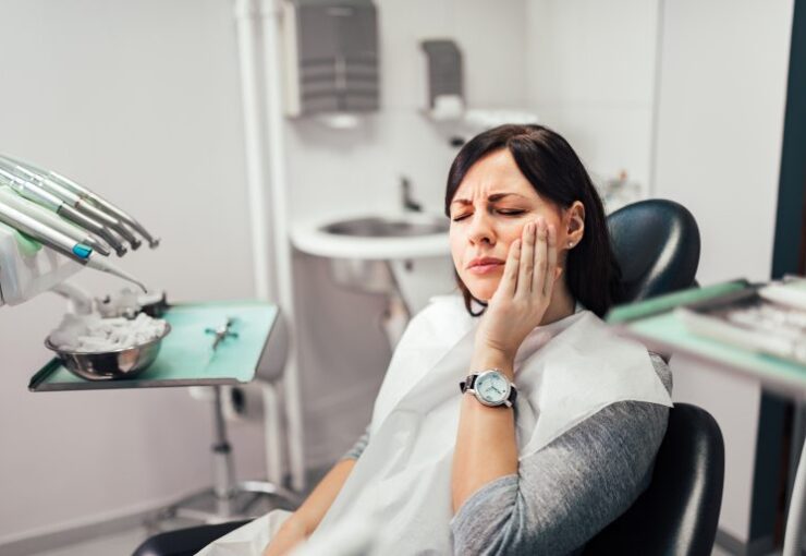 Woman holding her cheek in pain while visiting an emergency dentist in Fort Worth.